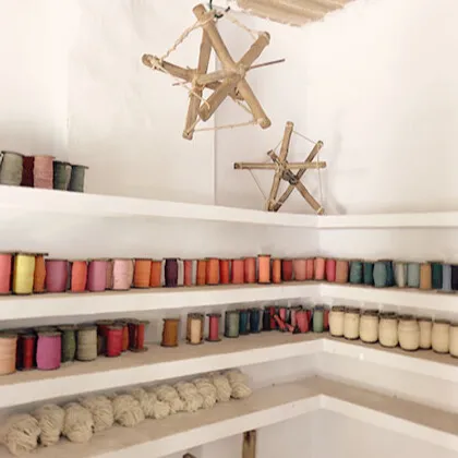 Shelves displaying cotton thread spools and framed portraits, including Mahatma Gandhi, at a traditional Khadi textile workspace in India