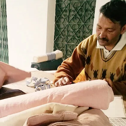 Artisan carefully inspecting handwoven Khadi cotton fabric at a rehabilitation center in the Himalayan foothills