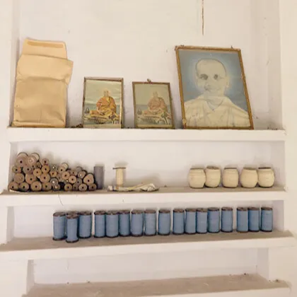 Shelves lined with colorful Khadi cotton yarn spools and traditional spinning tools at an Indian textile workshop