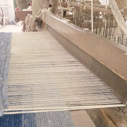 Close-up of a traditional handloom weaving blue Khadi cotton fabric at an Indian textile workshop