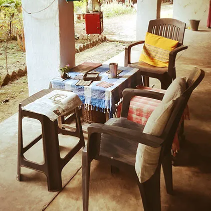 Outdoor veranda with plastic chairs and a table covered in handwoven Khadi cotton textiles at a rural Indian textile center